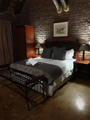 a bedroom with a large bed in a brick wall at Sundowners Game Lodge in Marble Hall