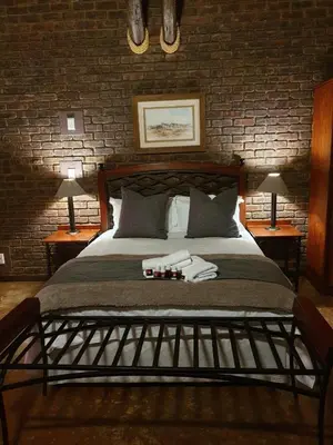a bedroom with a large bed with two lamps and bottles on it at Sundowners Game Lodge in Marble Hall