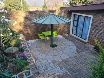 a patio with a table and a green umbrella at Mia Hills guest house in Hartbeespoort