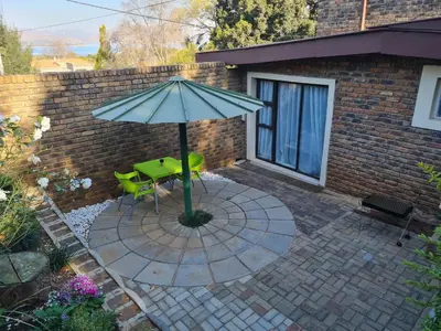 a patio with a green table and an umbrella at Mia Hills guest house in Hartbeespoort