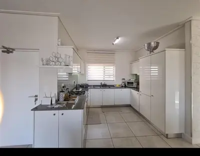a large white kitchen with white cabinets and appliances at Le Bon Dieu in Midrand