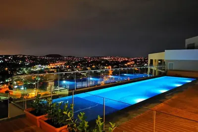 a swimming pool on the roof of a building at night at Comfort at 1503 Menlyn Maine Residences in Pretoria