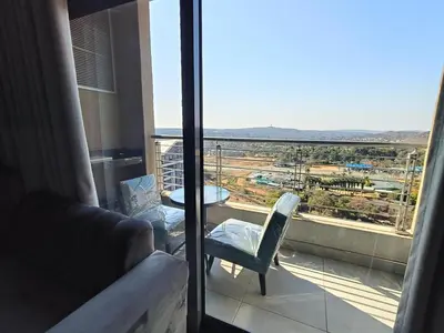 a room with a balcony with a view of a city at Comfort at 1503 Menlyn Maine Residences in Pretoria