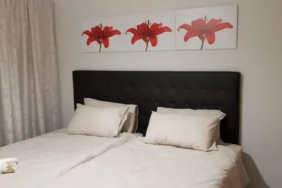 a bed with white sheets and red flowers on the wall at Blyde 3 bed Lagoon View Apartment in Pretoria