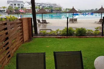 two chairs sitting in the grass near a swimming pool at Blyde 3 bed Lagoon View Apartment in Pretoria