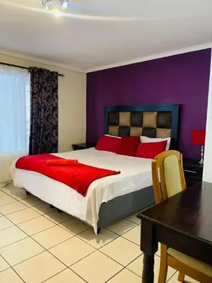 a bedroom with a large bed with a purple wall at @431 Rupert Street in Pretoria