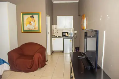 a living room with a chair and a kitchen at @431 Rupert Street in Pretoria