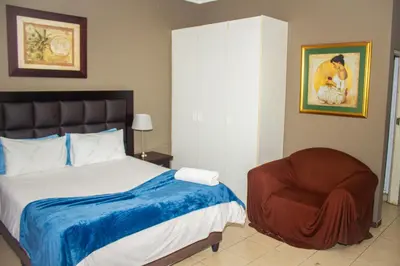 a bedroom with a bed and a chair at @431 Rupert Street in Pretoria