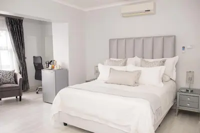 a white bedroom with a large bed with white pillows at Augusta Palms in Centurion