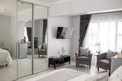 a bedroom with a bed and chairs and a mirror at Augusta Palms in Centurion
