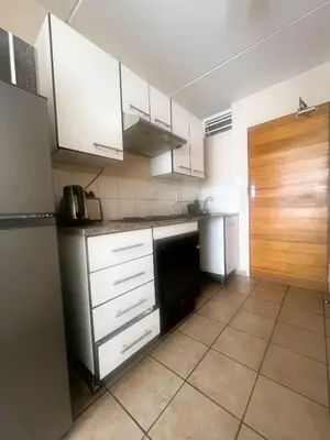 a kitchen with white cabinets and a black refrigerator at Smart and Cozy Studio with Netflix and Showmax in Pretoria