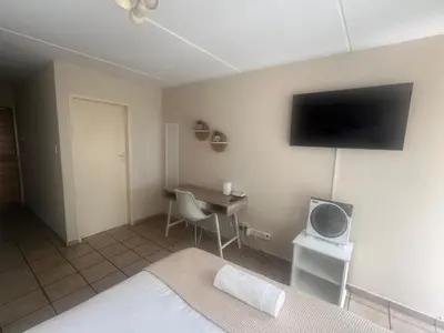 a bedroom with a bed and a desk with a tv at Smart and Cozy Studio with Netflix and Showmax in Pretoria