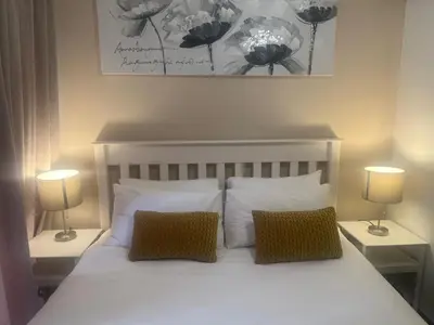 a bedroom with a white bed with two lamps at Smart and Cozy Studio with Netflix and Showmax in Pretoria