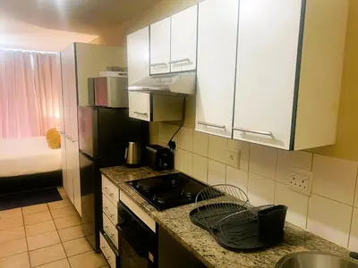 a small kitchen with a sink and a stove at Smart and Cozy Studio with Netflix and Showmax in Pretoria