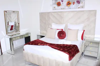 a bedroom with a large white bed with red pillows at ANGELOCEAN GUEST HOUSE in Witbank