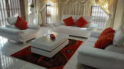 a living room with white furniture and red pillows at ANGELOCEAN GUEST HOUSE in Witbank