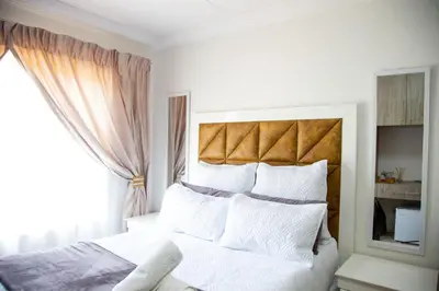 a bedroom with a white bed with a large window at ANGELOCEAN GUEST HOUSE in Witbank