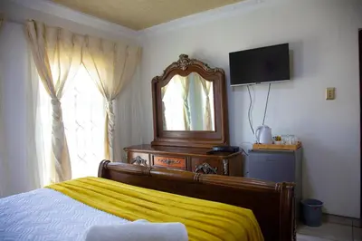 a bedroom with a bed and a mirror and a television at ANGELOCEAN GUEST HOUSE in Witbank