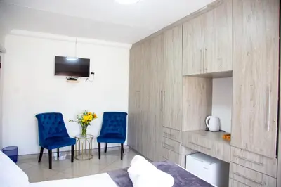 a bedroom with two blue chairs and a tv at ANGELOCEAN GUEST HOUSE in Witbank