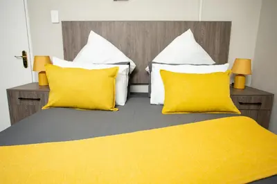 a bedroom with two yellow pillows and a bed at The Hide On Claremont in Pretoria