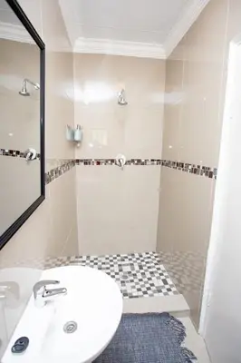 a white bathroom with a sink and a shower at The Hide On Claremont in Pretoria