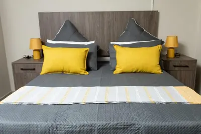 a bedroom with a bed with yellow pillows at The Hide On Claremont in Pretoria