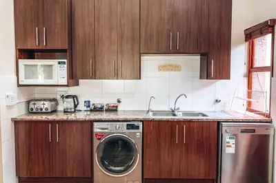 a kitchen with wooden cabinets and a washing machine at Pecanwood Golf Estate Home - Hartbeespoort in Hartbeespoort
