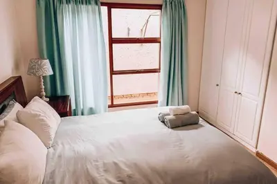 a bedroom with a white bed with a stuffed animal on it at Pecanwood Golf Estate Home - Hartbeespoort in Hartbeespoort