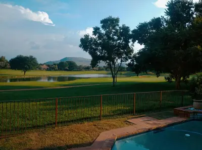 a swimming pool with a fence and a golf course at Pecanwood Golf Estate Home - Hartbeespoort in Hartbeespoort