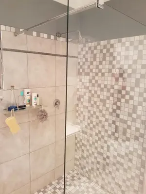 a shower with a glass door in a bathroom at Roosboompies Guest Suite in Centurion