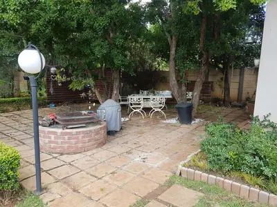 a patio with a table and chairs under a tree at Roosboompies Guest Suite in Centurion