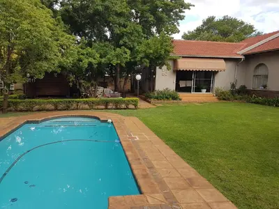 a swimming pool in the yard of a house at Roosboompies Guest Suite in Centurion