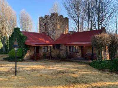 an old stone house with a red roof and a tower at Critchley Hackle - Tower rooms in Dullstroom