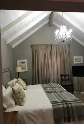 a bedroom with a large bed and a chandelier at Critchley Hackle - Tower rooms in Dullstroom