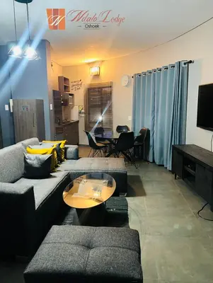 a living room with two couches and a table at Ndalo Lodge Oshoek in Oshoek