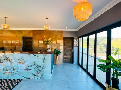 a kitchen with a large counter and glass walls at Ndalo Lodge Oshoek in Oshoek