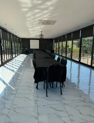 a conference room with a long table and chairs at Ndalo Lodge Oshoek in Oshoek