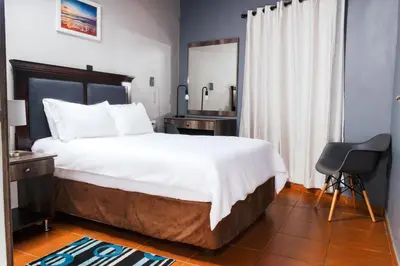 a bedroom with a large bed and a chair at Ndalo Lodge Oshoek in Oshoek