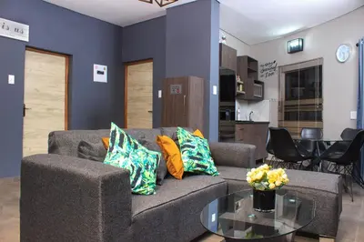 a living room with a couch and a table at Ndalo Lodge Oshoek in Oshoek
