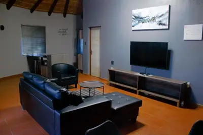 a living room with a couch and a flat screen tv at Ndalo Lodge Oshoek in Oshoek