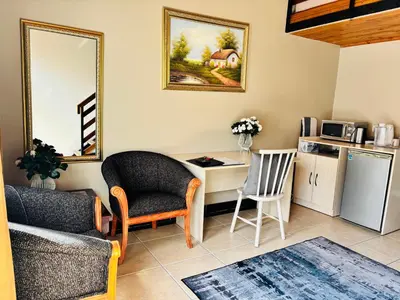 a living room with a table and a chair and a kitchen at Jabliano Guest House in Secunda