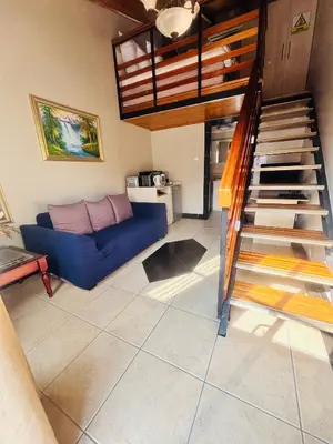a living room with a blue couch and a staircase at Jabliano Guest House in Secunda