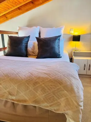 a bed with white sheets and pillows in a room at Jabliano Guest House in Secunda