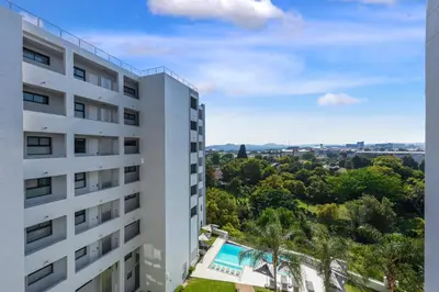 an apartment building with a swimming pool and trees at The Regency Apartments in Pretoria