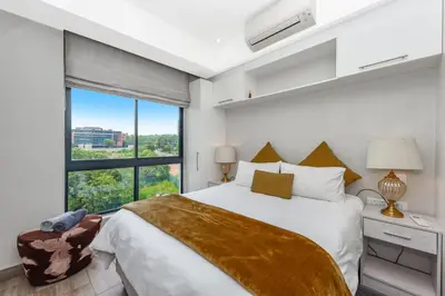 a bedroom with a large bed and a large window at The Regency Apartments in Pretoria