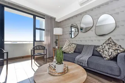 a living room with a couch and two mirrors at The Regency Apartments in Pretoria