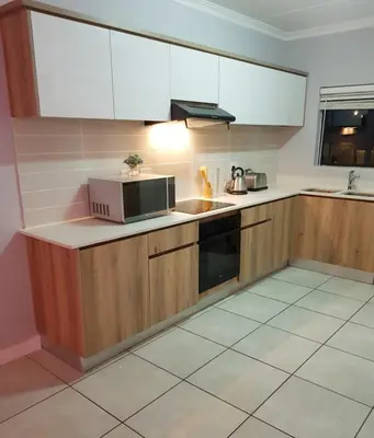a kitchen with wooden cabinets and a microwave at Apartment 432 @ The Blyde Riverwalk Pretoria in Pretoria