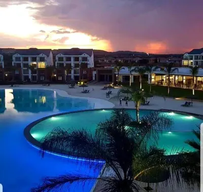 a large swimming pool with a sunset in the background at Apartment 432 @ The Blyde Riverwalk Pretoria in Pretoria