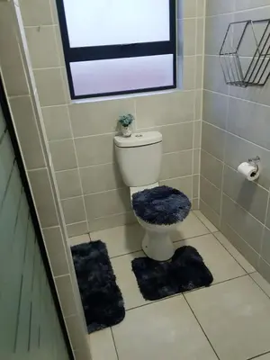 a bathroom with a toilet and two rugs on the floor at Apartment 432 @ The Blyde Riverwalk Pretoria in Pretoria