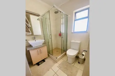 a bathroom with a shower and a toilet and a sink at Phoenix Rising Apartment in Midrand